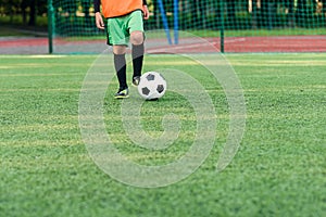 Soccer player kicking ball on field. Soccer players on training session. Close up footballer feet kicking ball on grass.