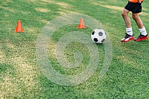 Soccer player kicking ball on field. Soccer players on training session. Close up footballer feet kicking ball on grass.