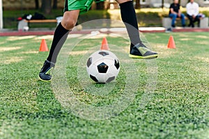 Soccer player kicking ball on field. Soccer players on training session. Close up footballer feet kicking ball on grass.