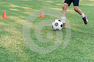 Soccer player kicking ball on field. Soccer players on training session. Close up footballer feet kicking ball on grass.