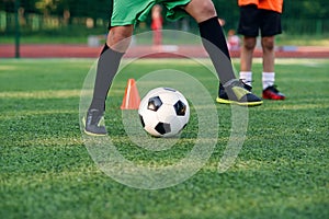 Soccer player kicking ball on field. Soccer players on training session. Close up footballer feet kicking ball on grass.