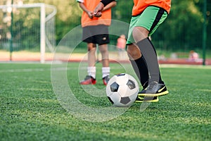 Soccer player kicking ball on field. Soccer players on training session. Close up footballer feet kicking ball on grass.