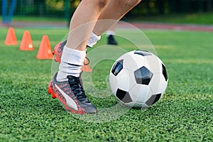 Soccer player kicking ball on field. Soccer players on training session. Close up footballer feet kicking ball on grass.