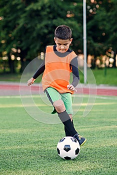 Soccer player kicking ball on field. Soccer players on training session. Teen footballer kicking ball on green grass.