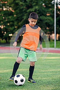 Soccer player kicking ball on field. Soccer players on training session. Teen footballer kicking ball on green grass.