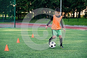 Soccer player kicking ball on field. Soccer players on training session. Teen footballer kicking ball on green grass.