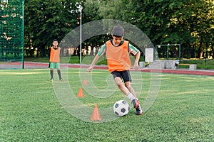 Soccer player kicking ball on field. Soccer players on training session. Teen footballer kicking ball on green grass.