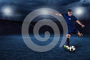 Soccer player kicking ball in a large stadium at night