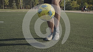 Soccer player legs bouncing ball on the pitch