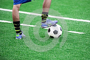 Soccer player's feet stepping onto a soccer ball