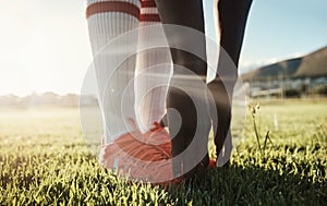 Soccer player, stretching legs on grass and hands on shoes on pitch for sport fitness training start. Football, health