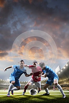 Soccer players in action on sunset stadium background