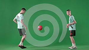 Soccer players on chroma key green screen background. Male professional football players playing with ball, hitting with