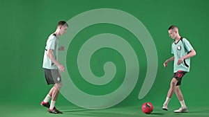Soccer players on chroma key green screen background. Male professional football players playing with ball, hitting it