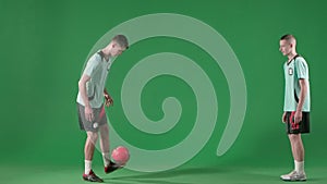 Soccer players on chroma key green screen background. Male professional football players playing with ball, hitting with