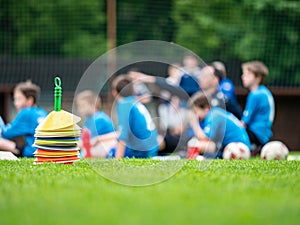 Soccer players rest  sitting between cone markers on green