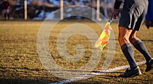 Soccer referee assistant moves at sideline with flag at hands. Blur green field,nature backdrop, close up view, banner, space.