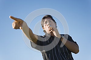 Soccer referee blowing whistle and pointing