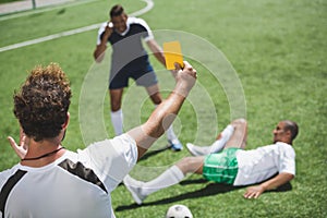 Soccer referee showing yellow card to players during game