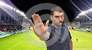 soccer referee with whistle showing stop gesture