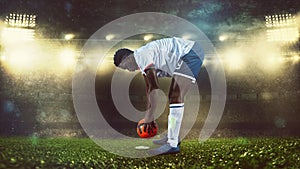 Soccer scene at night match with player in white and uniform placing the ball to kick