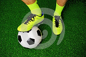 Soccer shoes and football on the green grass