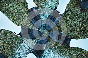Soccer, sport shoes and teamwork with people together on a grass field for motivation or competition. Closeup, above and