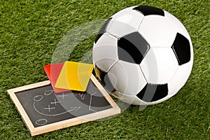 Soccer sports ball with game strategy drawing blackboard and yellow and red referee cards on grass background