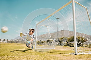 Soccer, sports and children with a goalkeeper saving a shot during a competitive game on a grass pitch or field