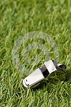 Soccer sports chrome whistle on grass background - penalty, foul or sports concept