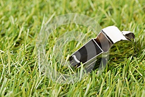 Soccer sports chrome whistle on grass background - penalty, foul or sports concept