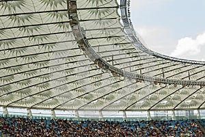 Soccer stadium inside view. football field, empty stands, a crowd of fans, a roof against the sky