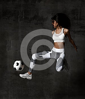 Soccer woman player jumps and hit the ball strike in the middle on concrete loft wall