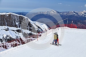 Sochi, Russia - April 1, 2014: Young couple stands embracing on ski track in Gorky Gorod mountain ski resort on snowy Caucasus