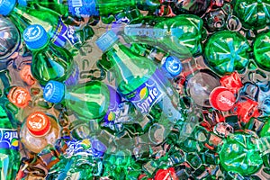 Small colorful plastic bottles of Sprite, Coca Cola and Fanta non-alcoholic drinks getting cool in water with ice bricks. A close