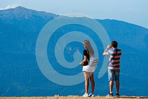 Sochi, Russia, 17 September 2020 - young man and woman standing on observation deck in mountains back to the camera, travel