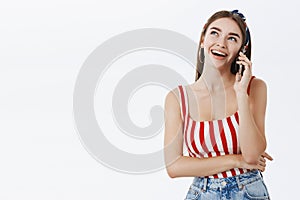 Sociable stylish and talkative good-looking woman in striped top and headband tilting head and gazing up while being