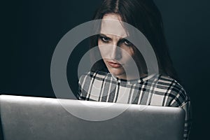 Social bullying concept. Sad and empty woman using computer and feeling depressed. Harrasment concept.