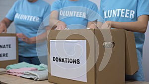 Social center volunteers putting clothes in donation boxes, altruism generosity