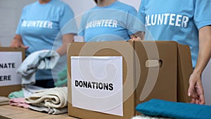 Social center volunteers putting clothes in donation boxes, altruism generosity