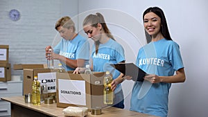 Social center workers preparing food donation boxes making notes, volunteering