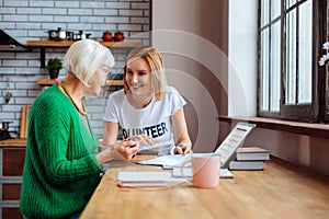 Social department worker helping grey-haired dame with overdue loan papers.