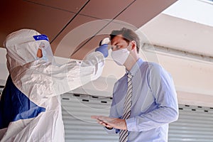 Social distance concept. Officer wearing a respirator mask to use infrared forehead thermometer to check fever body temperature