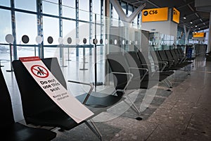 Social distance notice sign on airport terminal chairs. Safety measures from covid-19 pandemic