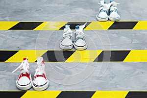 Social distancing concept. Sneakers and warning tape on the asphalt background.