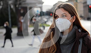 Social distancing respected. Portrait of young woman wearing FFP2 KN95 face mask in winter clothes outdoors photo