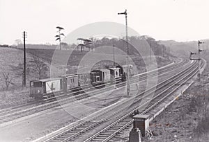 Vintage black and white photo of a static line of train carriages and wagons on track 1950s
