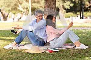 Social Media Addiction. Mature Couple Using Smartphones During Outdoor Date In Park