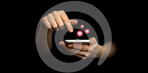 Social media concept. Hands using smartphone with like notification icons. Social networking, black background photo