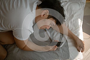 Social media depression. Sad and depressed man lie on the sofa with mobile phone.